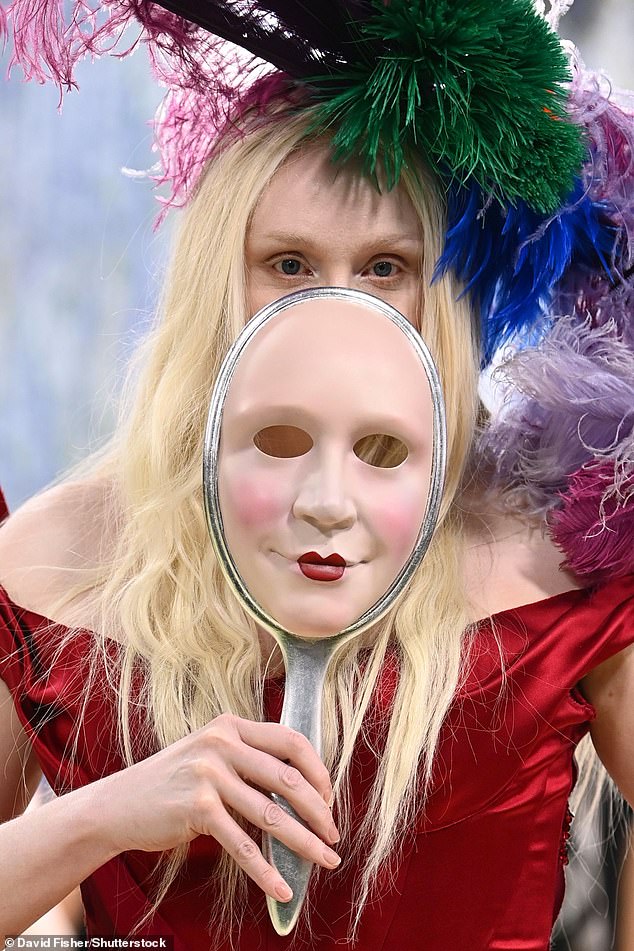 Pushing the fashion envelope she added a striking ostrich feathered hat and carried opera mask of her own face