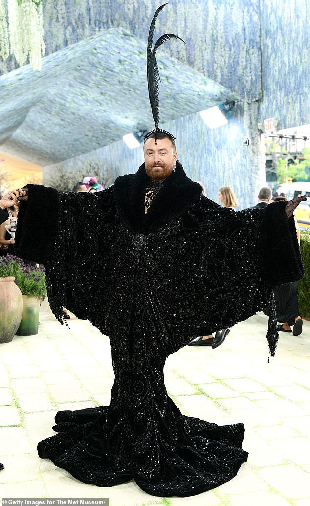 Looking like a quill pen! Artist Sam Smith wore a black bedazzled outfit that featured an overzied, dramatic cape top lined with fur and a mermaid-style, bottom-hugging hem. They paired the look with a large matching headpiece that included two extremely tall black feathers