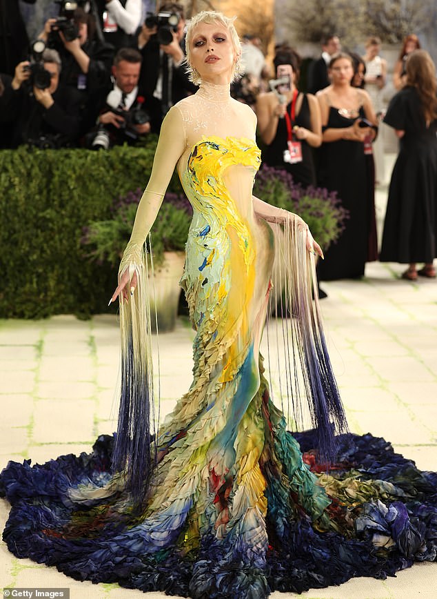 Tassels gone wrong! Emma Chamberlain wore a very dramatic, over-the-top Mugler gown that resembled paint and brush strokes on the body and into the ruffled hem. The sleeves featured long tassels and shredded detailing that continued into the train of her gown. She completed the look with a super dark smokey eye and a dark nude lip