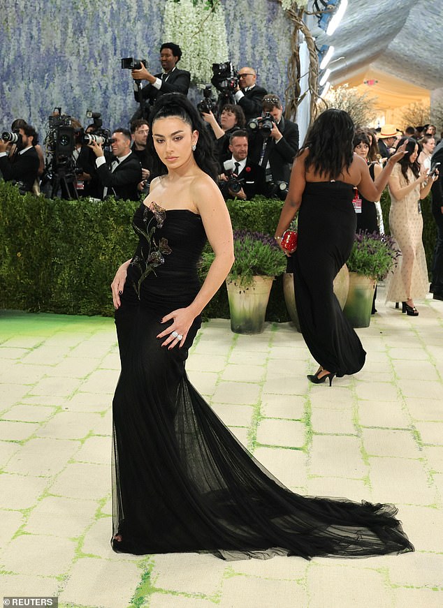 Boring! Singer Charli XCX wore a strapless, curve-hugging black gown made by Saint Laurent with an intricate floral detail at the top of the dress. She wore her hair in a high ponytail and sported minimal jewelry