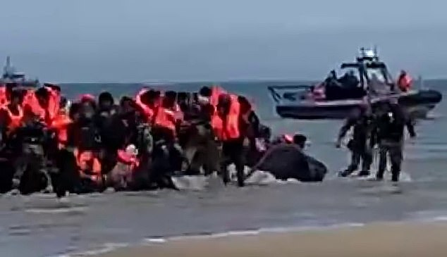 Later in the sequence, about 25 migrants disembark the deflating vessel and return to the beach