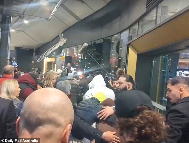 The large black-clad men shielded one woman who was allowed to walk free from the media