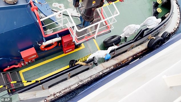 At least five people with full protective gear, white overalls, boots and face masks, were seen disembarking from the ship into a small vessel