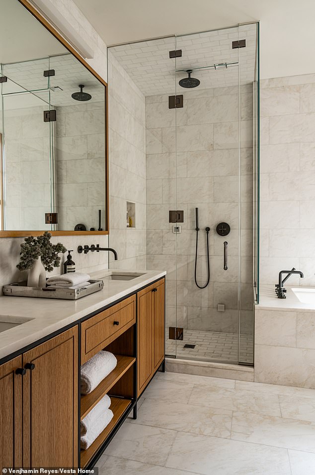 One of the bathrooms has marble-tiled flooring as well as a double sink with wooden cabinetry. A modern walk-in shower with elegant finishings is next to a bathtub
