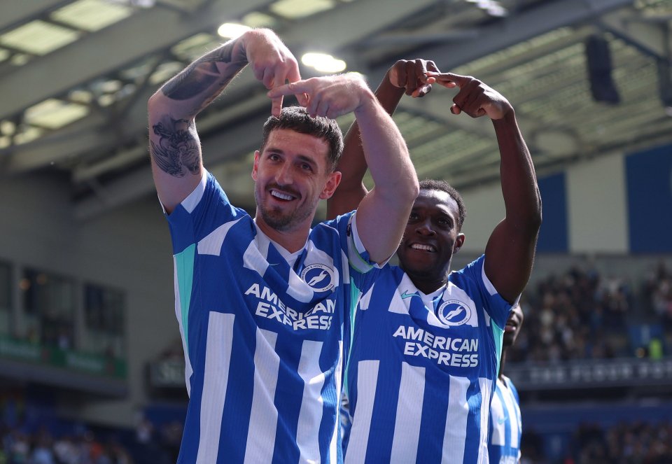 Two Brighton & Hove Albion players, one light-skinned with tattoos and one dark-skinned, celebrate by forming a heart shape with their hands.