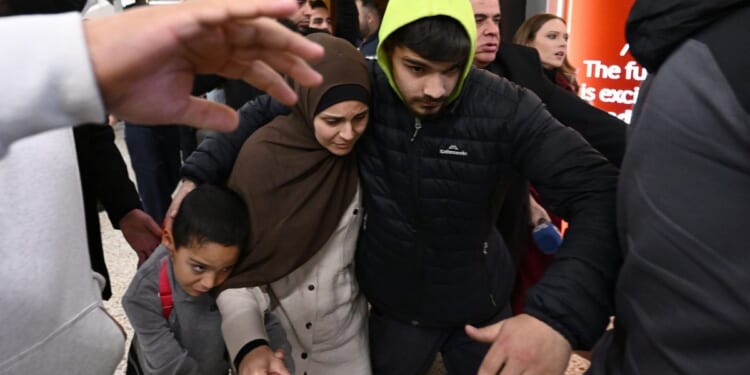A woman who is accused of ties to the Islamic state is escorted through a crowd by supporters on Thursday, May 7, 2026. (Joel Carrett / AAP Image via AP)