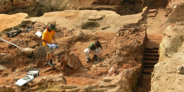 A stock photograph of two archeologists at work at a dig site.