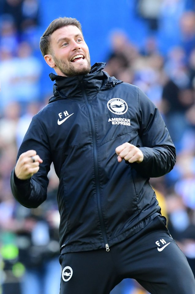 A man wearing a black Brighton and Hove Albion jacket celebrating on the sidelines.