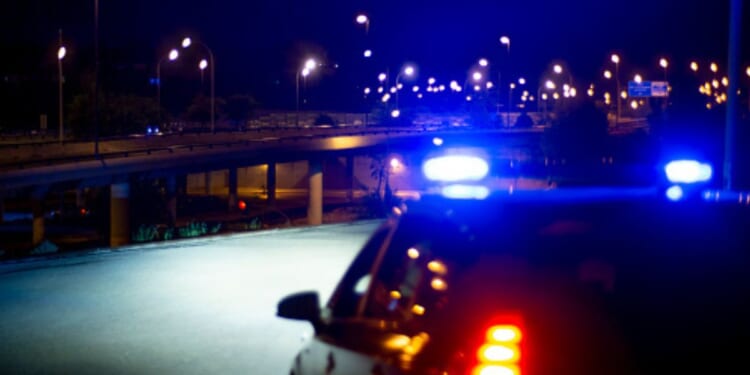 Cop lights flash as they park on a roadway.