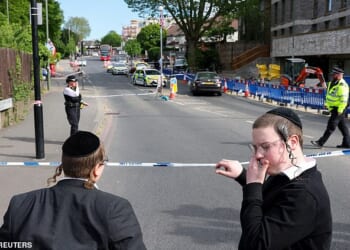 Orthodox Jews stand by a police cordon following the stabbing incident in the Golders Green area, which is home to a large Jewish population on April 29