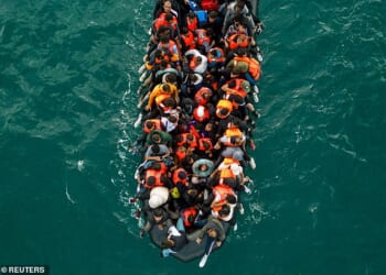 An inflatable dinghy pictured carrying migrants makes its way towards England