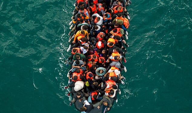 An inflatable dinghy pictured carrying migrants makes its way towards England