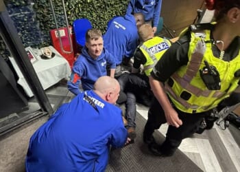 Pictured: police at the scene as shelter volunteers help restrain a 49-year-old man after he allegedly headbutted a worker who refused to let him film himself giving food to the homeless