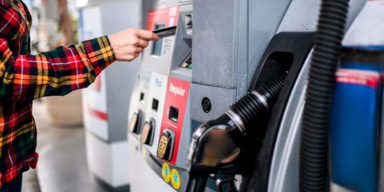 A person pays for gas at a gas station pump using a card.