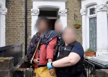 A woman (pictured in the pink coat) was arrested today by Criminal and Financial Investigations section of the Home Office's Immigration Enforcement Team