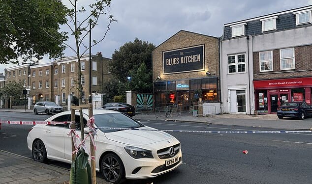 A police cordon on Acre Lane in Brixton, south London. Police are investigating the possibility that the stabbing of a man and the shooting of four people in the same area of south London are linked