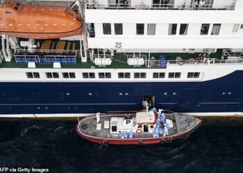 Aerial view shows health personnel assisting patients onto a boat from the cruise ship MV Hondius, while stationary off the port of Praia