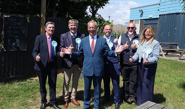 Reform UK leader Nigel Farage poses with local candidates in a pub garden in Jaywick, near Clacton-on-Sea, eastern England on May 7, 2026. UK polling stations opened on May 7 in local elections set to heap more pressure on beleaguered Labour Prime Minister Keir Starmer and showcase the rise of hard-right and left-wing populists. (Photo by Chris Radburn / AFP via Getty Images)